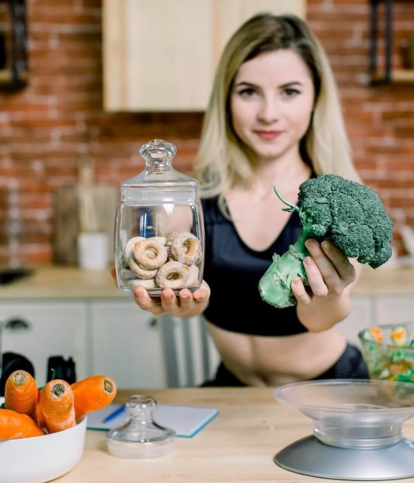 young-woman-in-black-sport-clothes-choosing-between-broccoli-or-junk-food-bagels-healthy-clean-1.jpg
